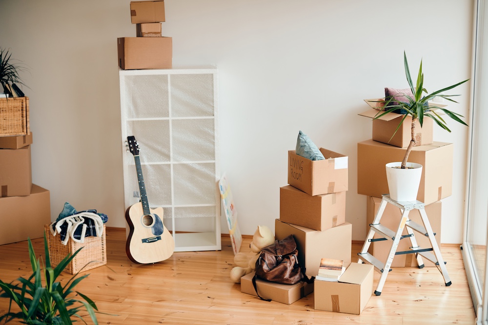 Cardboard boxes and belongings in a living room of a new home.